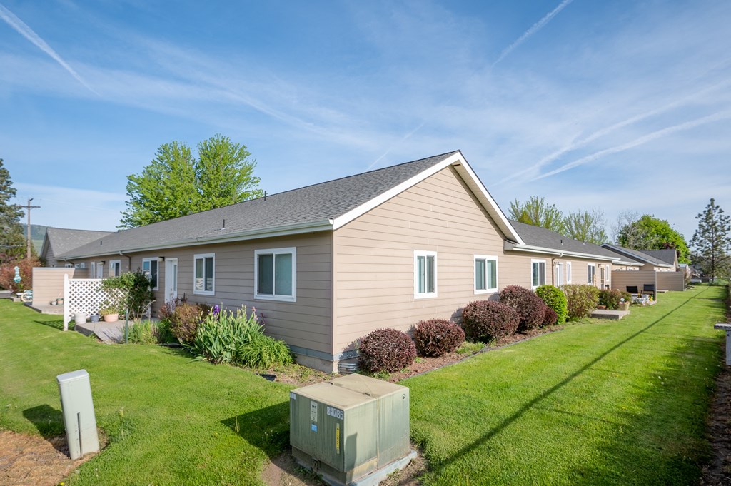 a beige house with a yard and a green lawn
