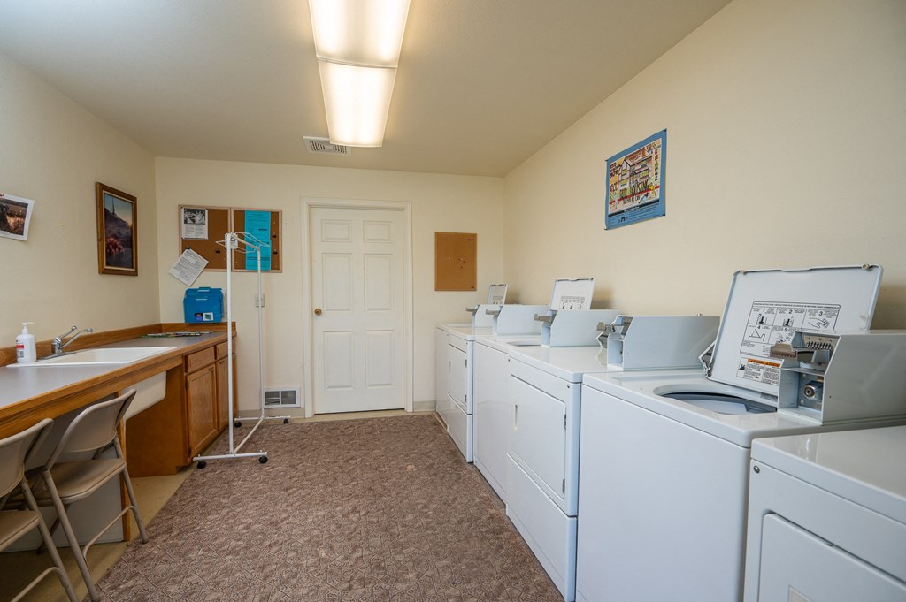 a laundry room with washers and dryers and a table with chairs
