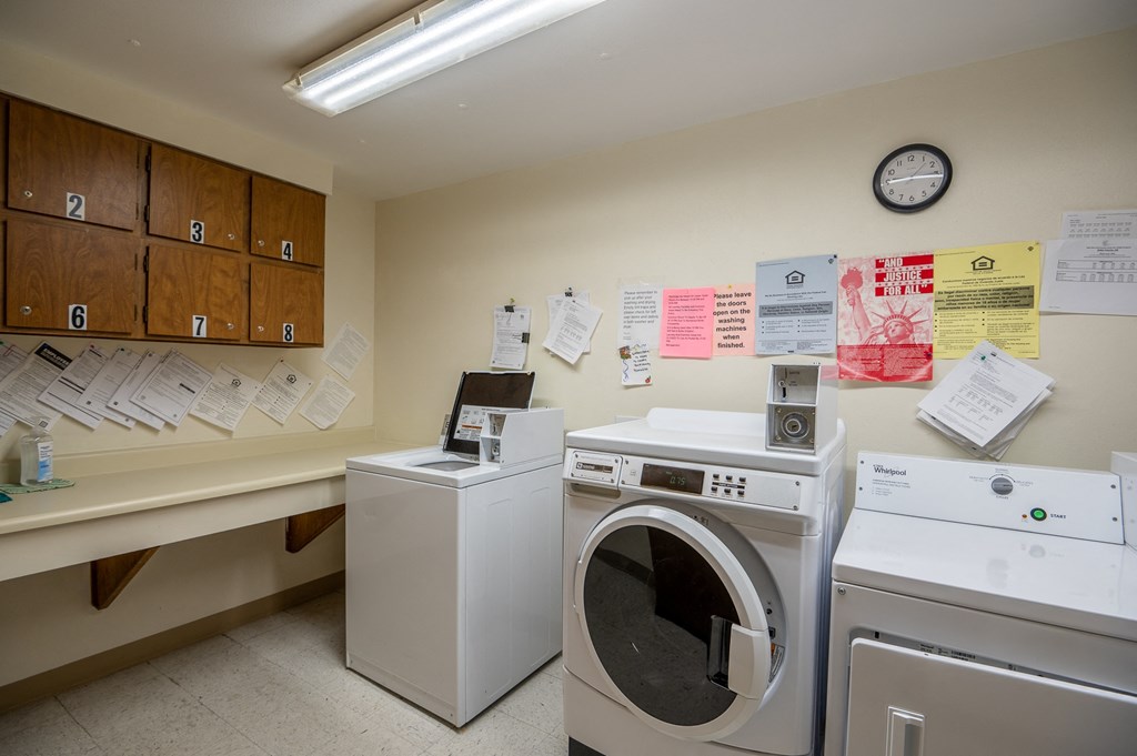 a laundry room with two washing machines and a counter with a clock on the wall