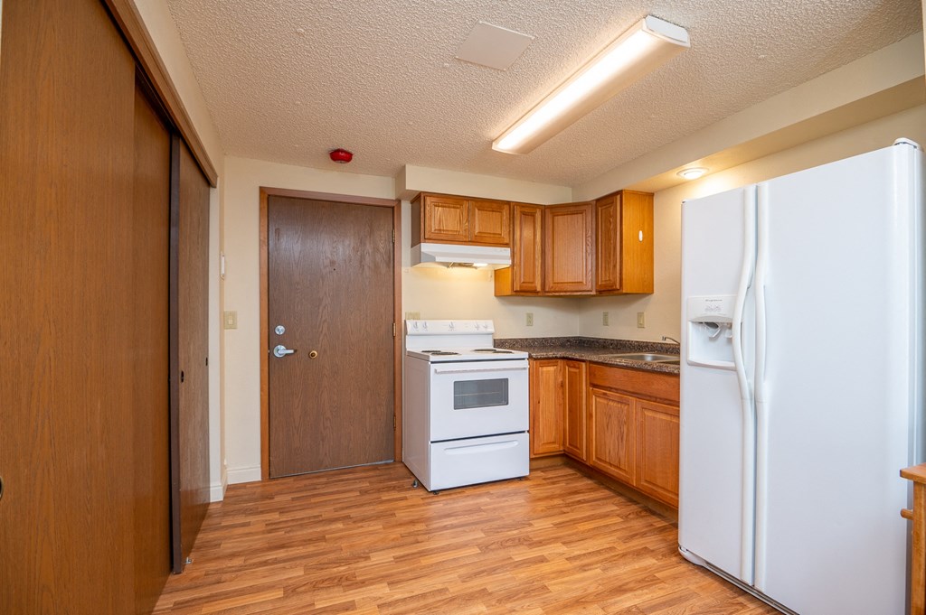 a kitchen with white appliances and wooden cabinets and a refrigerator