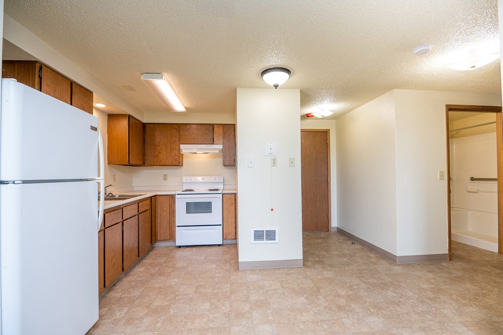 an empty kitchen with white appliances and wooden cabinets