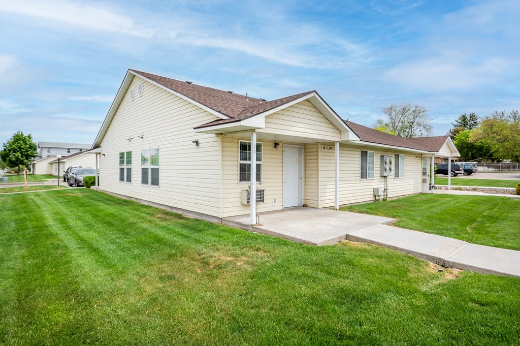 the front of a white house with a lawn and a driveway
