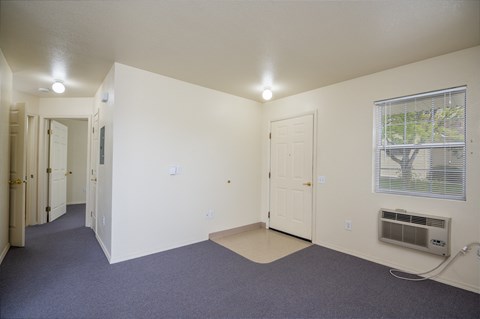 an empty living room with a door and a window and a air conditioner