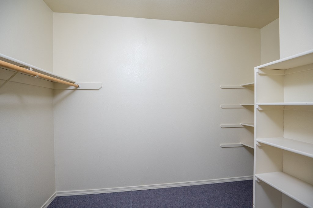 a walk in closet in an empty room with shelves