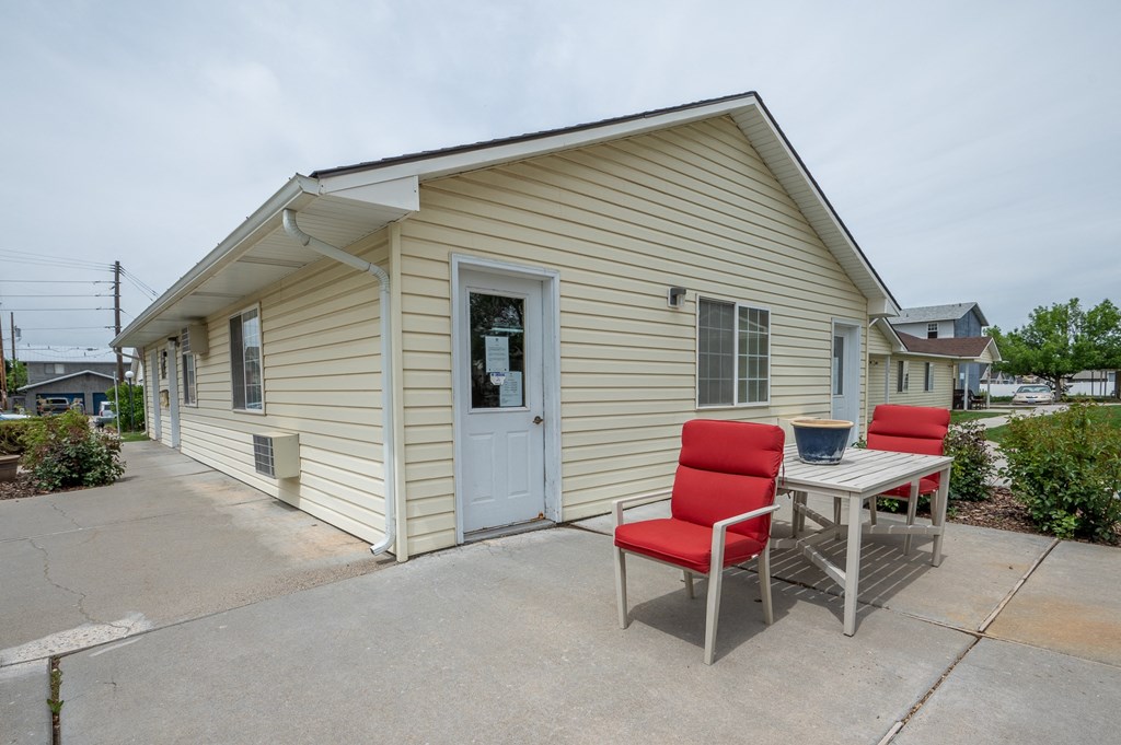 a small yellow house with a table and chairs on a patio