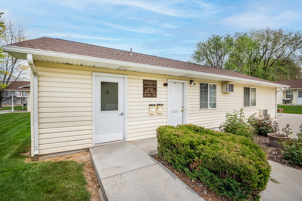 a small yellow house with a white door and a sidewalk
