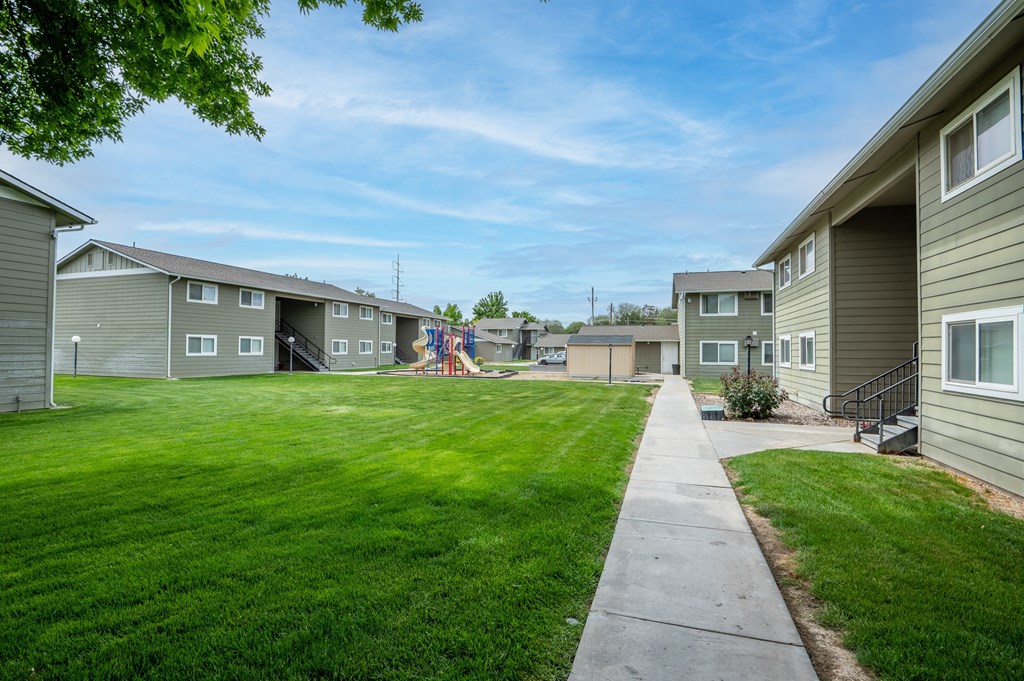 the view of a yard between two rows of houses with grass