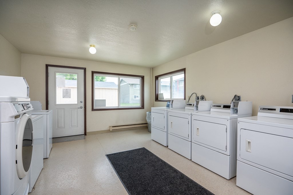 a washer and dryer room with laundry machines and windows