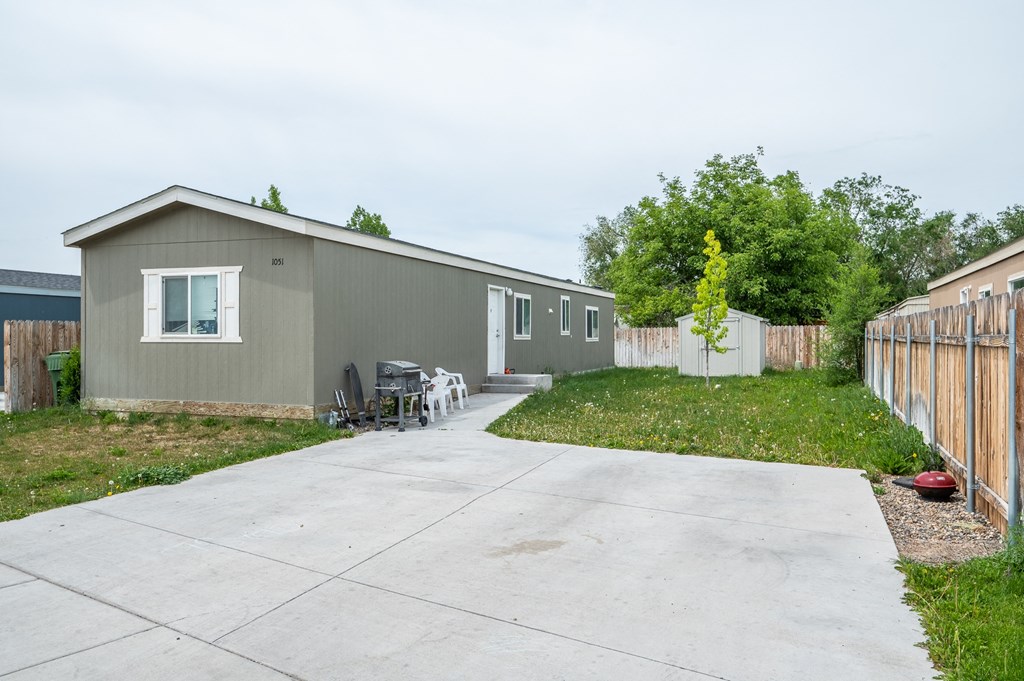a gray house with a driveway and a yard with a fence