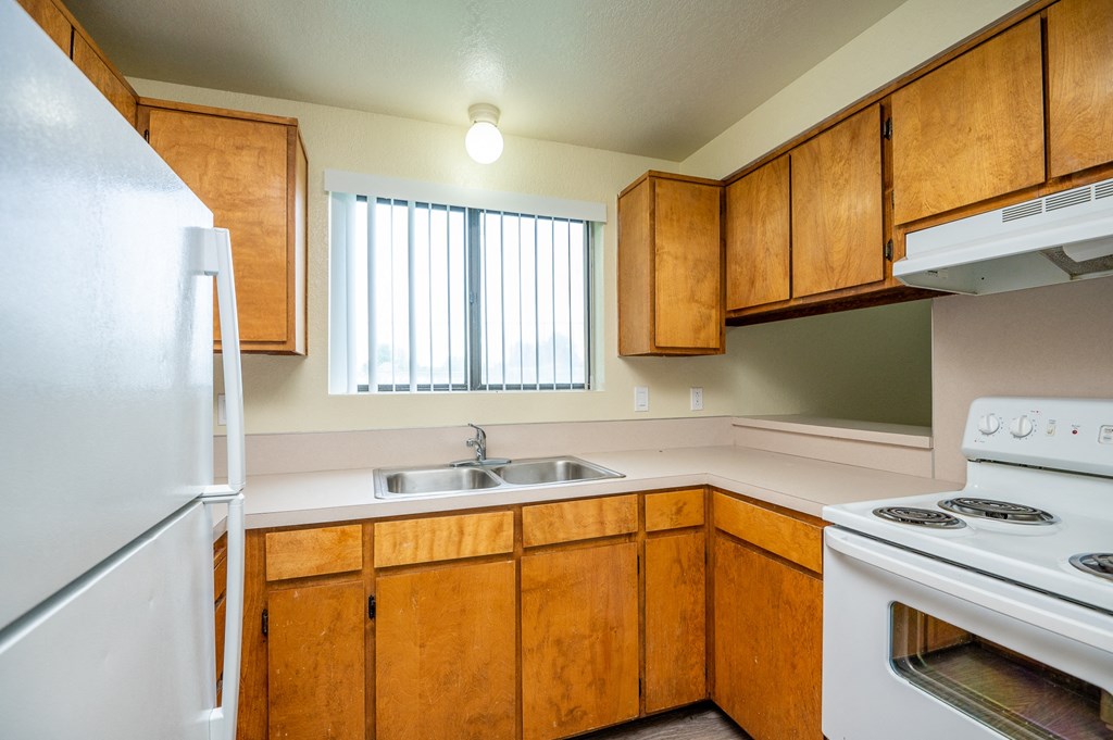 an empty kitchen with white appliances and wooden cabinets