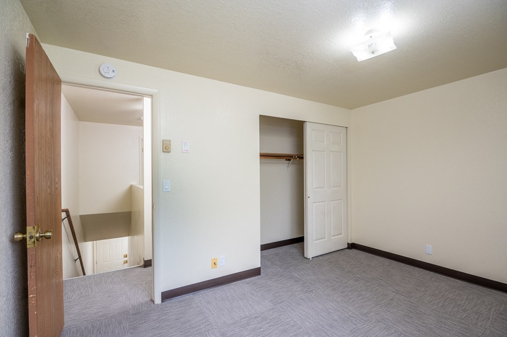 the living room of an empty apartment with a door to the closet