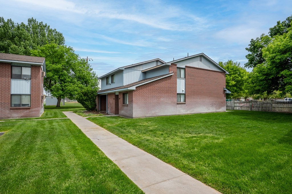 a brick house with green grass and a sidewalk