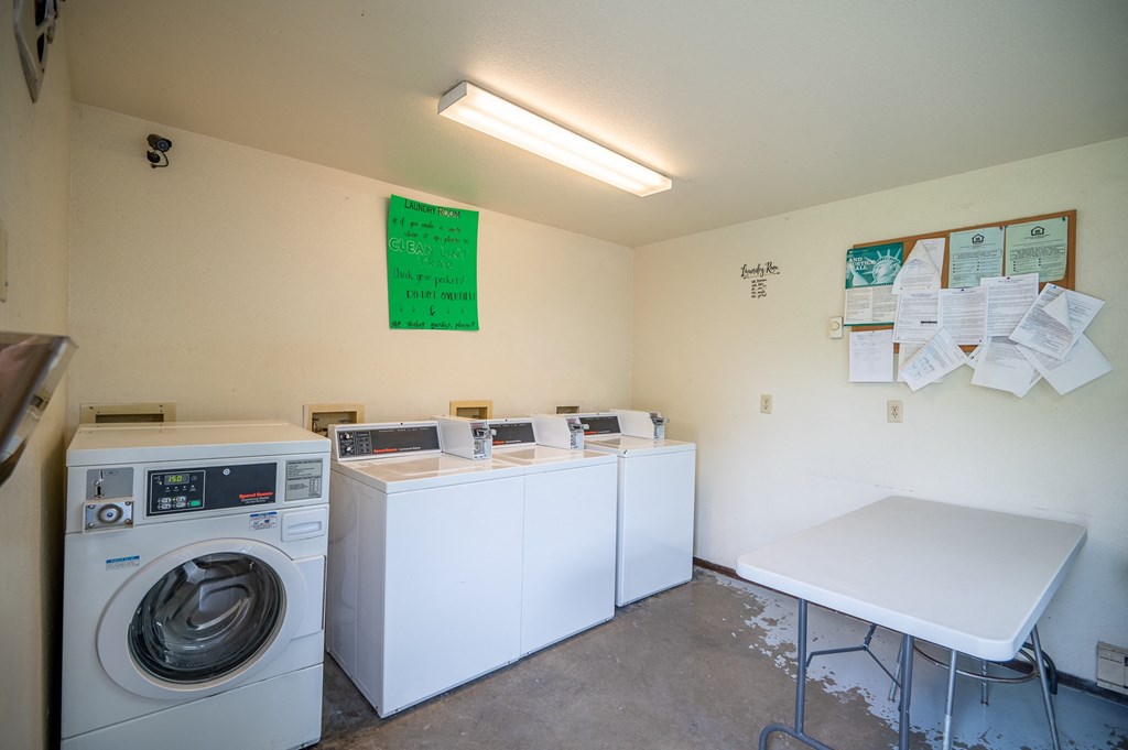 a laundry room with four washing machines and a table