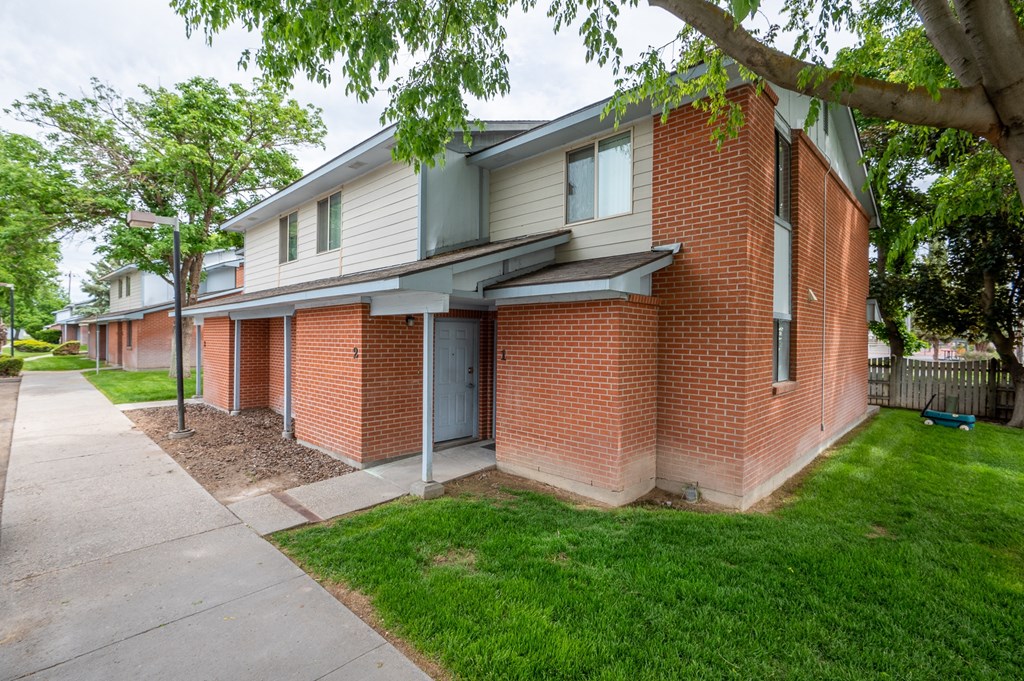 the side of a brick house with a sidewalk