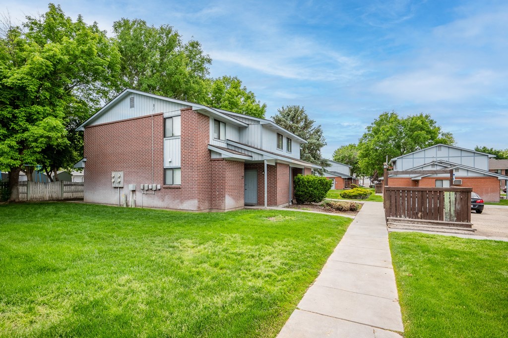 a brick house with a yard and a sidewalk