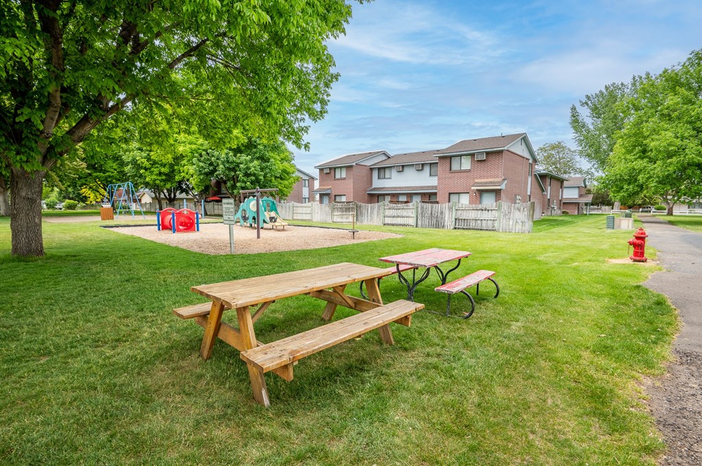 a park with picnic tables and a playground in front of a house