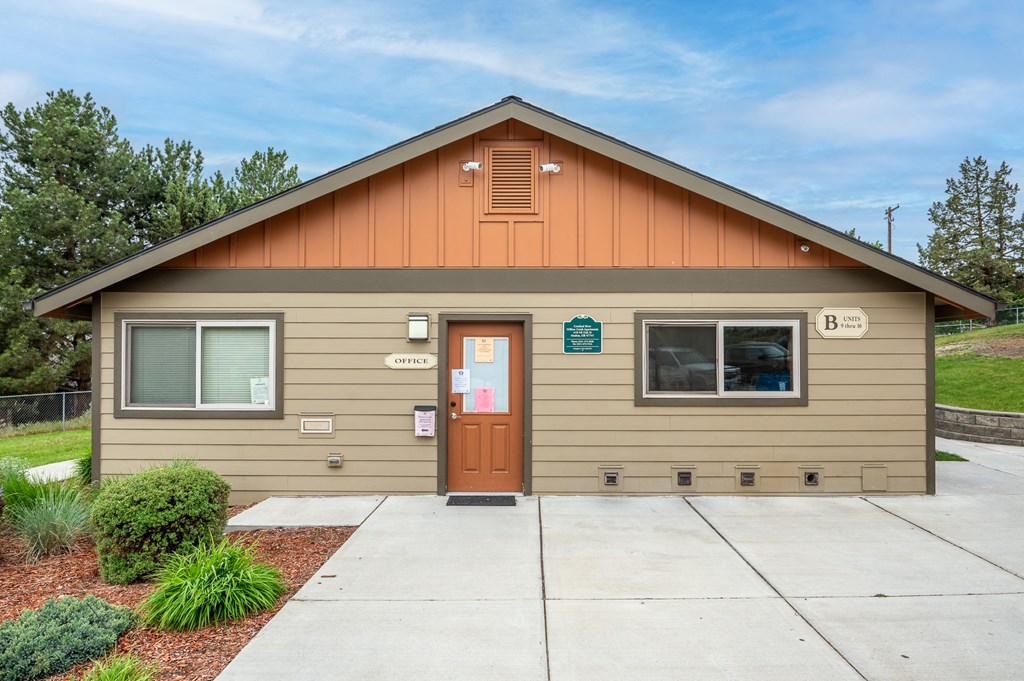 the front of a tan building with a sidewalk and a door
