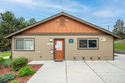 the front of a tan building with a sidewalk and a door