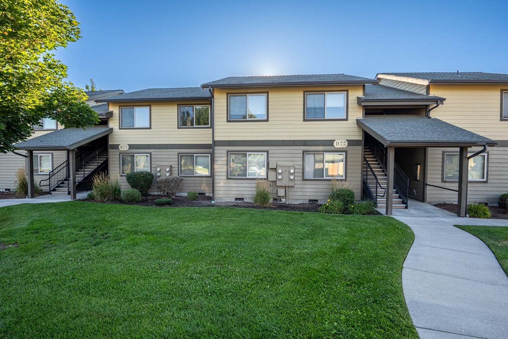 A sunny day at a two-story residential building with a well-kept lawn.