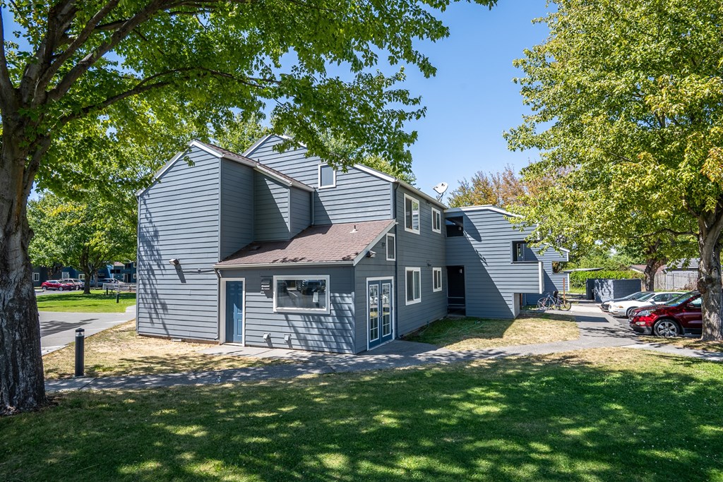 A grey house with a red car parked in front.