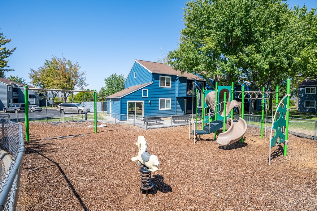A playground with a blue slide and a brown ground.