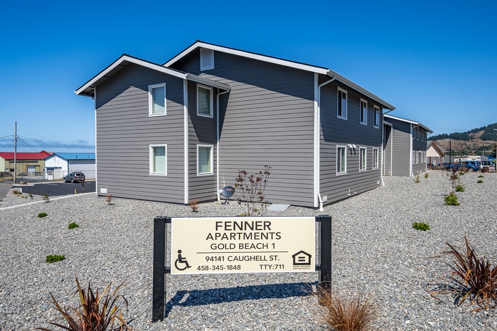 A sign in front of a building that says "Fennner Apartments Gold Beach 1".