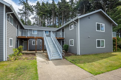 A grey house with a staircase leading to the second floor.