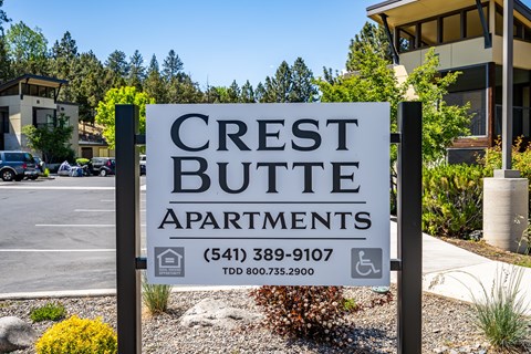 A sign for Crest Butte Apartments is displayed in front of a building.