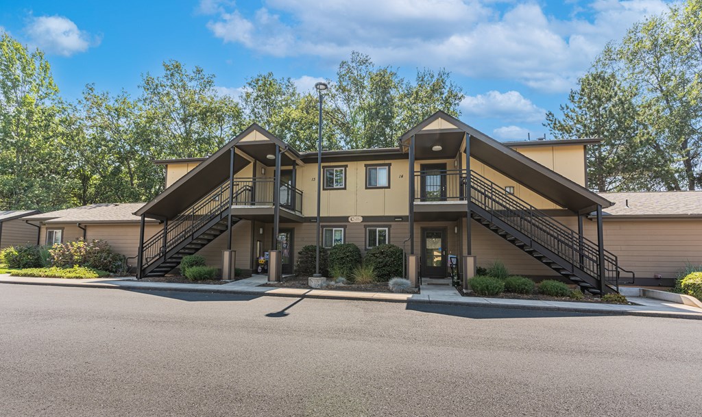 the front of a house with stairs and a parking lot
