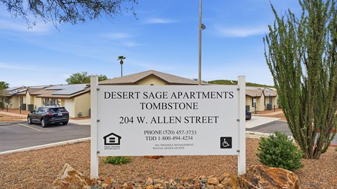 A sign for Desert Sage Apartments in Tombstone stands in front of the building.