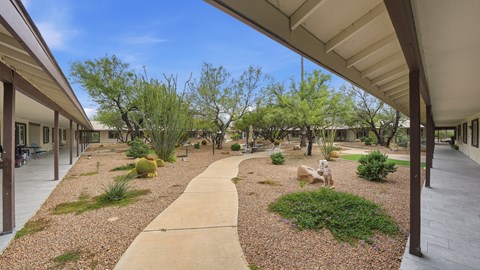 A garden area with a gravel path and a grassy area with a statue.