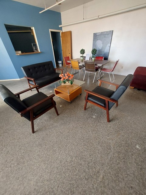 A living room with a black sofa, a coffee table, and a chair.