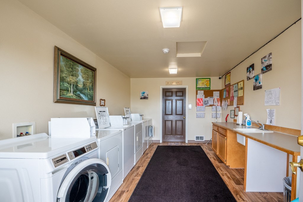 A laundry room with a washer and dryer on the left and a counter on the right.