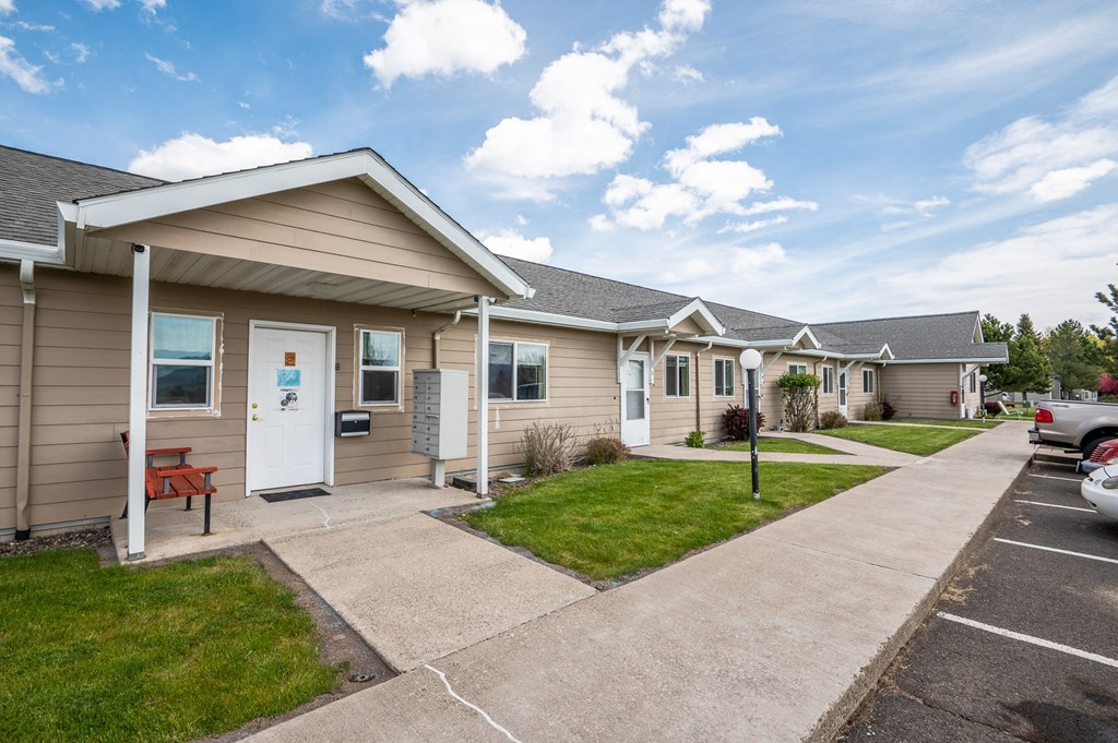 A small building with a white door and a bench outside.