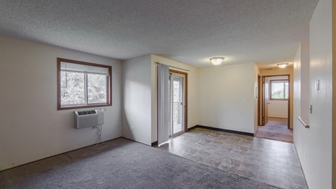 an empty living room with a door to a hallway and a window