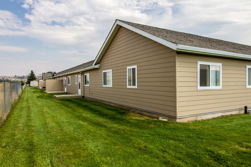 a row of houses on the side of a green lawn