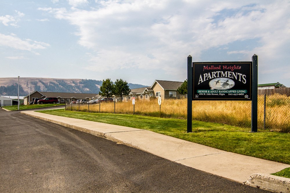a sign for the apartments on the side of the road