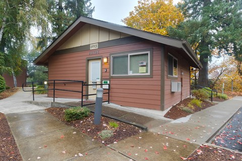 a small brown building with a sidewalk in front of it
