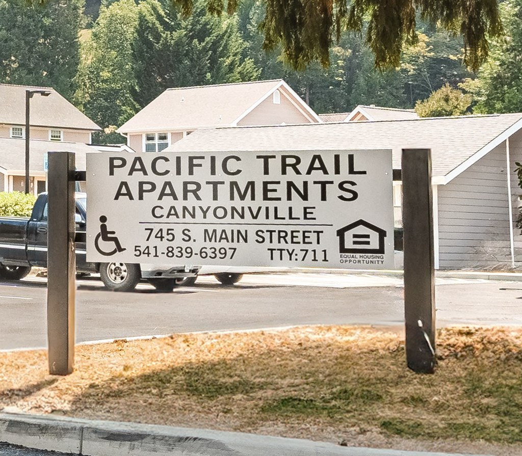 a sign for pacific trail apartments in front of a truck