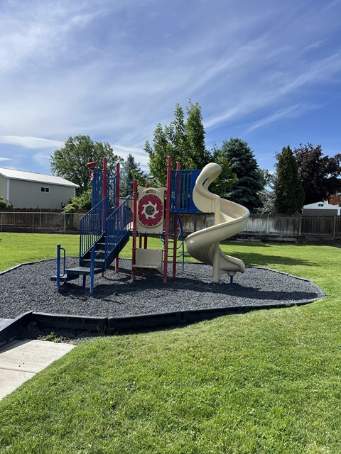 A playground with a slide and a red and white sign.