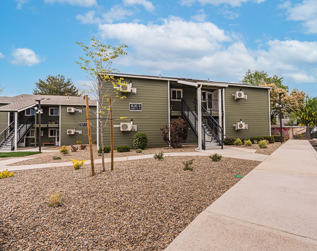 A small building with a grey roof and a small tree in front of it.