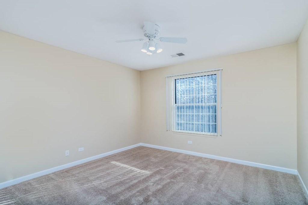 an empty room with a window and a ceiling fan
