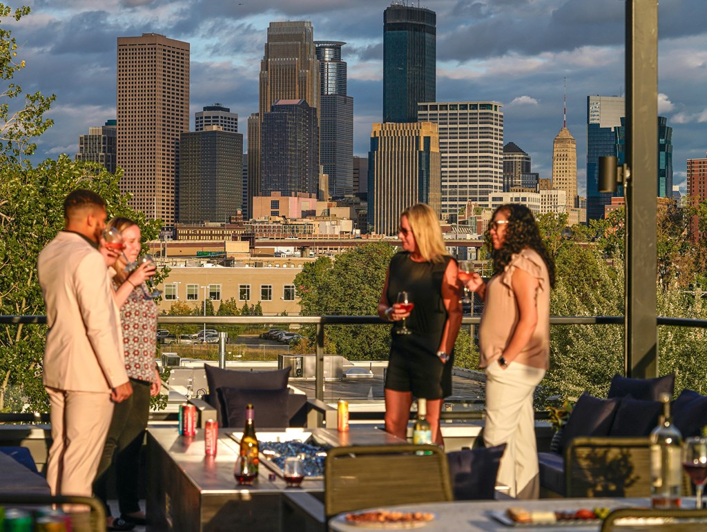 a group of people on a rooftop terrace with a city skyline in the background