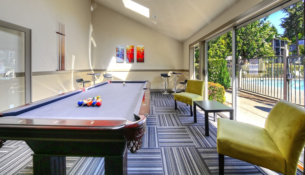 a games room with a pool table and chairs