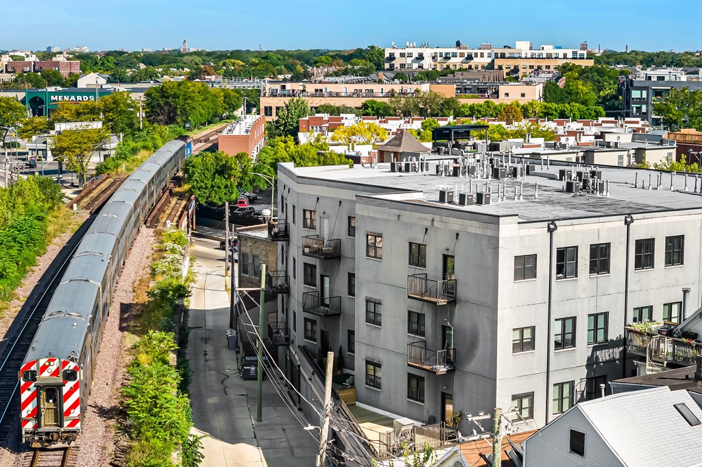 A train is coming down the tracks in a city.