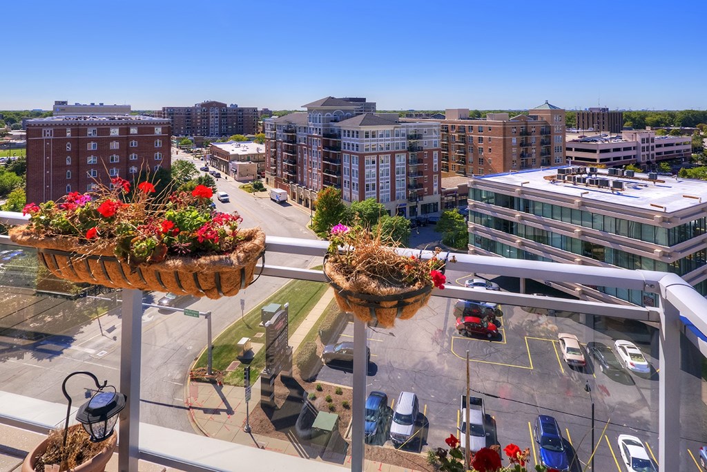 a view of a city from a balcony with baskets of flowers