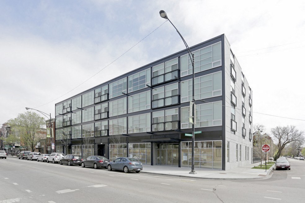 a large building on the corner of a street with cars parked