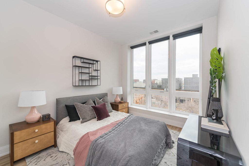 a bedroom with a large window and a bed with pillows