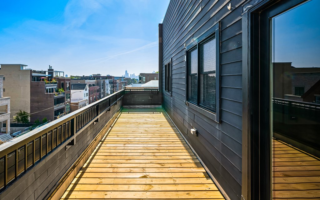 A wooden deck with a railing and a building with a window in the background.