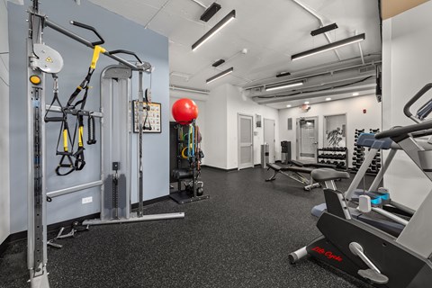 a gym with weights and other equipment on the floor and a red ball in the